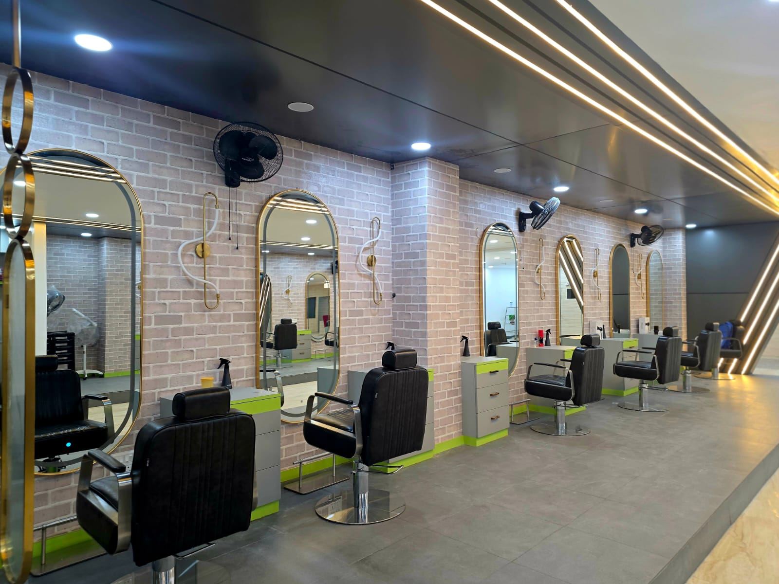 Orane Salon styling stations with arched gold-framed mirrors on exposed brick